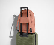 The Everywhere Zip Backpack in Clay Pink on top of an Away carry-on suitcase