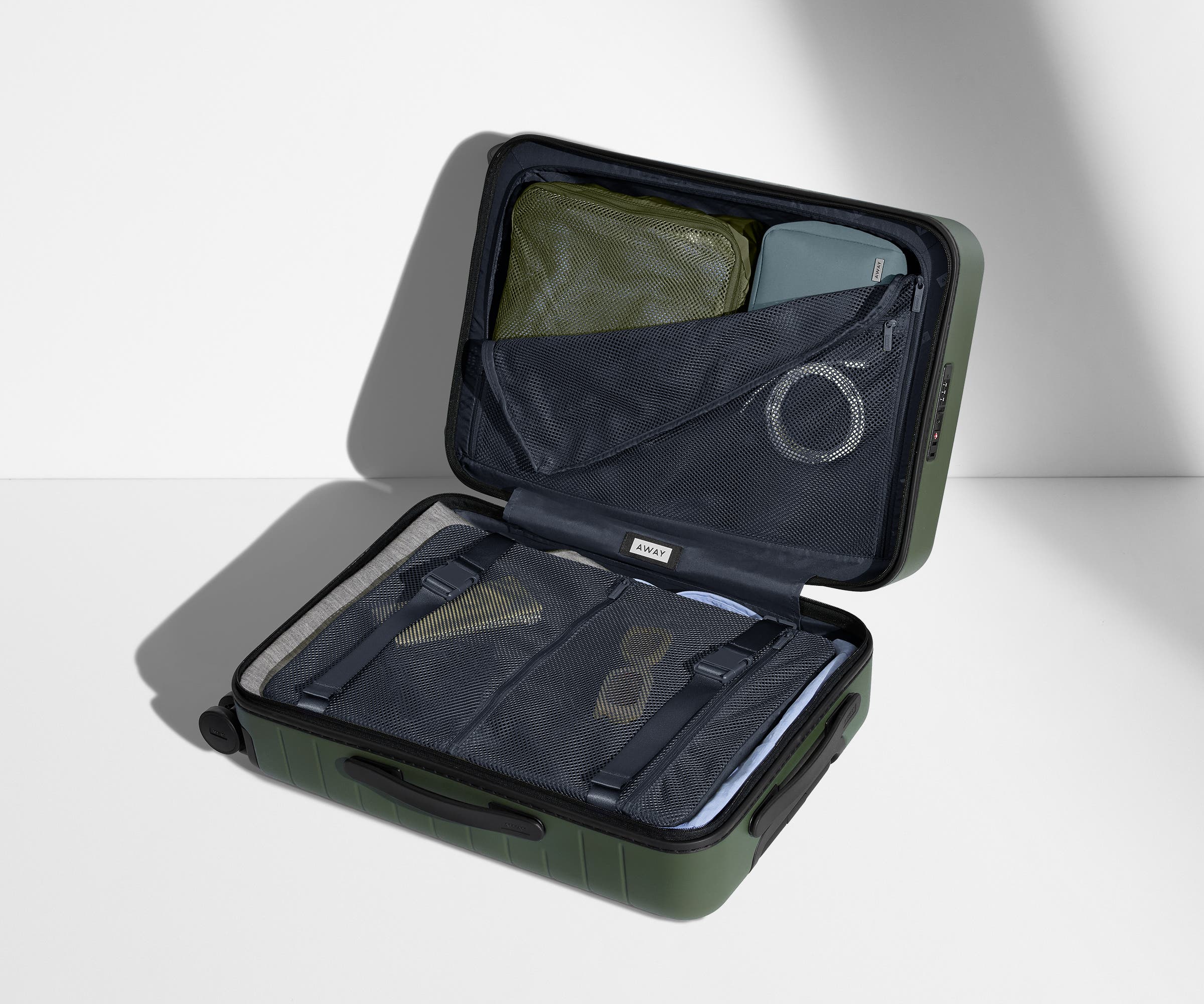 The Bigger Carry-On suitcase in Olive Green shown open on its side and packed with Away's packing organizers to show capacity and the interior compression system, designed to help you pack more in
// 
Our signature interior compression system allows you to stay more organized. Paired with The Insider Packing Cubes.