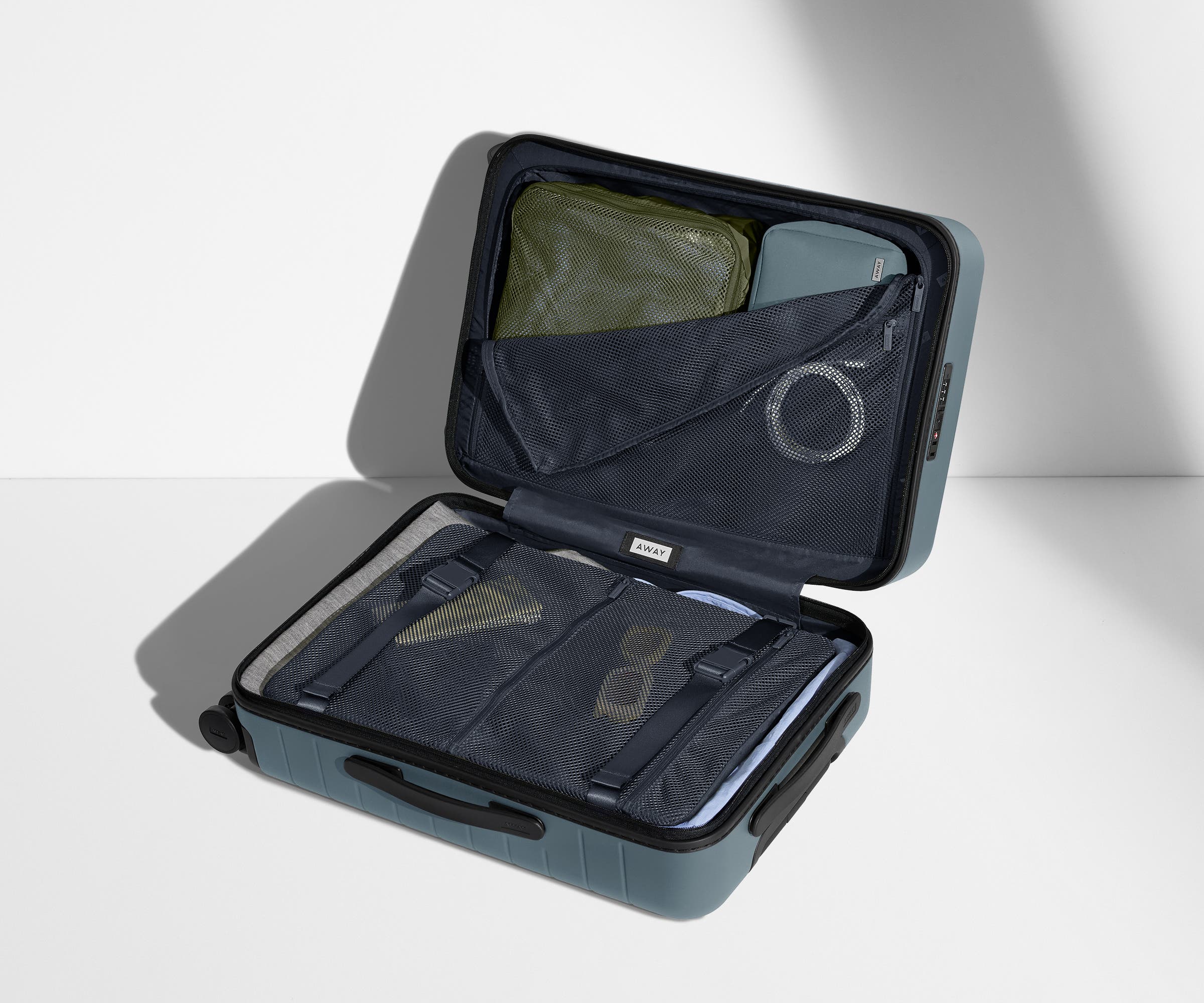 The Bigger Carry-On suitcase in Coast Blue shown open on its side and packed with Away's packing organizers to show capacity and the interior compression system, designed to help you pack more in
// 
Our signature interior compression system allows you to stay more organized. Paired with The Insider Packing Cubes.