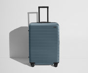 Front product view of The Medium Flex suitcase in Coast Blue with raised handle