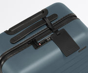 The Bigger Carry-On suitcase in Coast Blue shown shown from above highlighting TSA-approved combination lock and recycled leather luggage tag