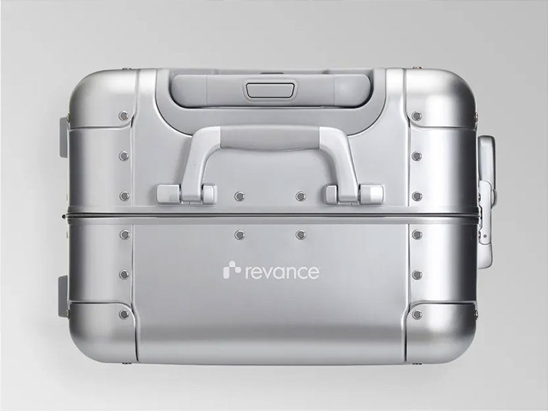 A logo engraved on top of an Away Aluminum suitcase