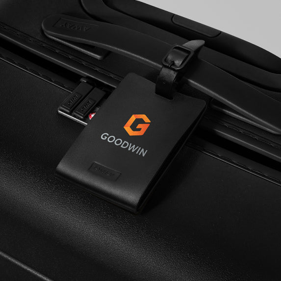 a close crop of a luggage tag with a printed logo attached to a black suitcase