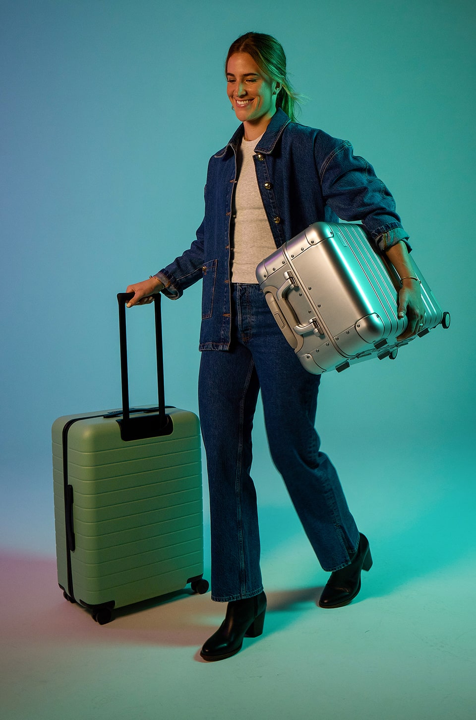 A photo of Sabrina carrying two Away suitcases on a blue gradient background