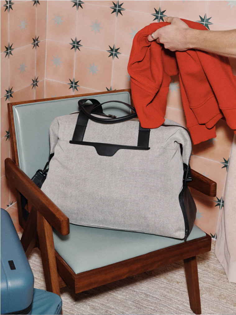 Person packing a red sweater into a Transit Canvas Weekender duffle bag