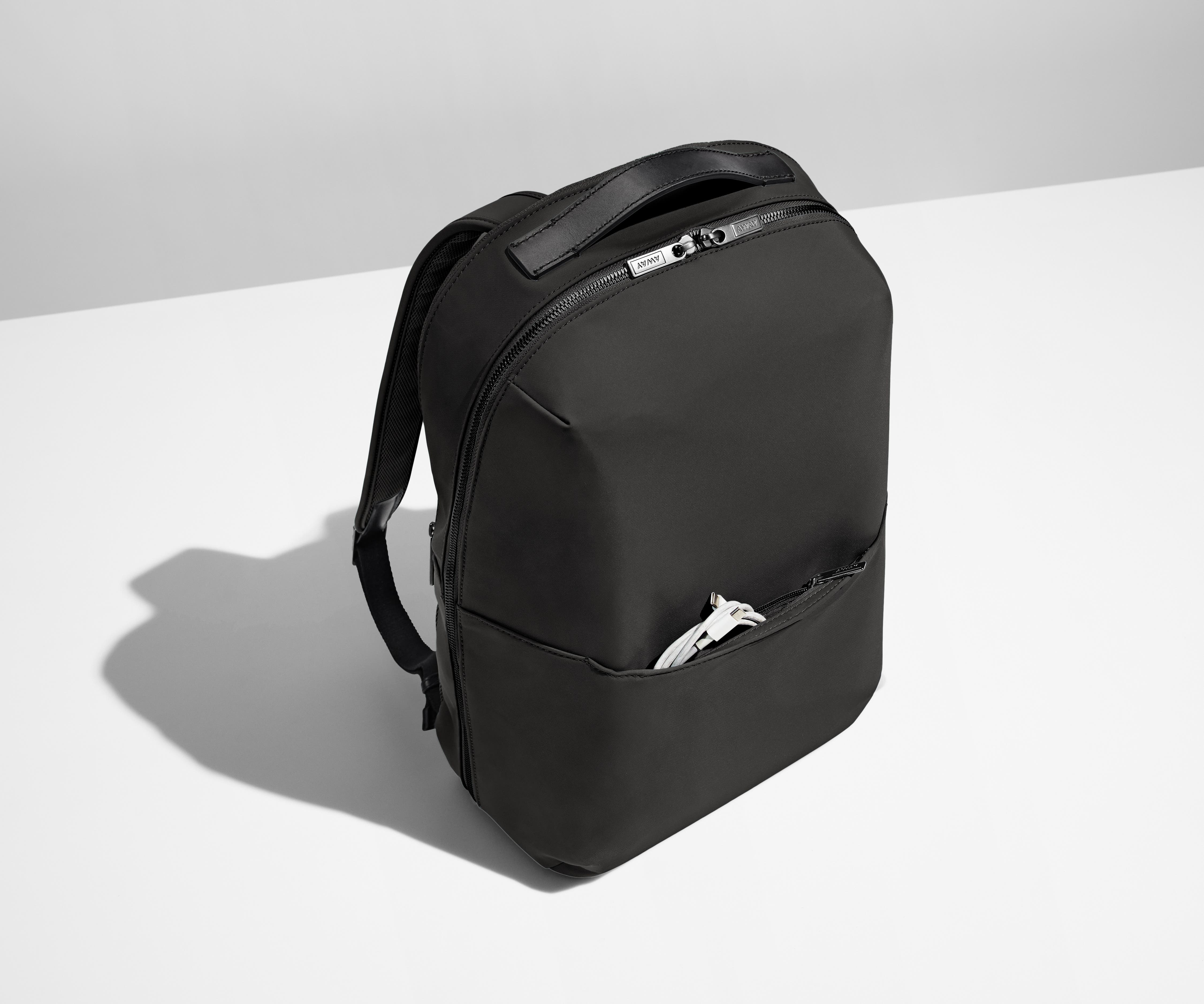 Angled product view of the Everywhere Zip Backpack with a charging cord in the exterior front pocket