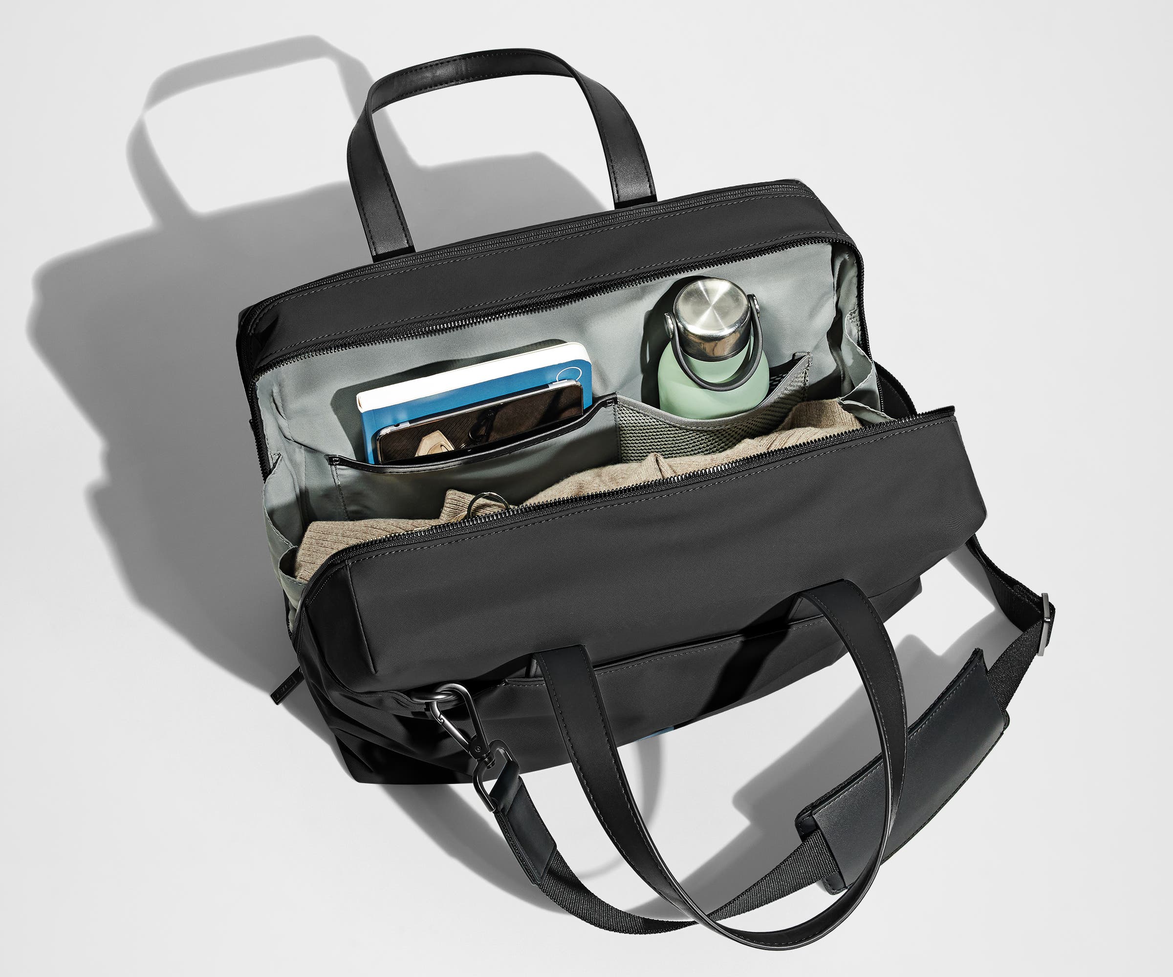 Main compartment packed with a light sweater, notebook, tablet, and water bottle. The detachable shoulder strap is clipped onto the bag.
// The Everywhere Bag features a detachable padded shoulder strap. 