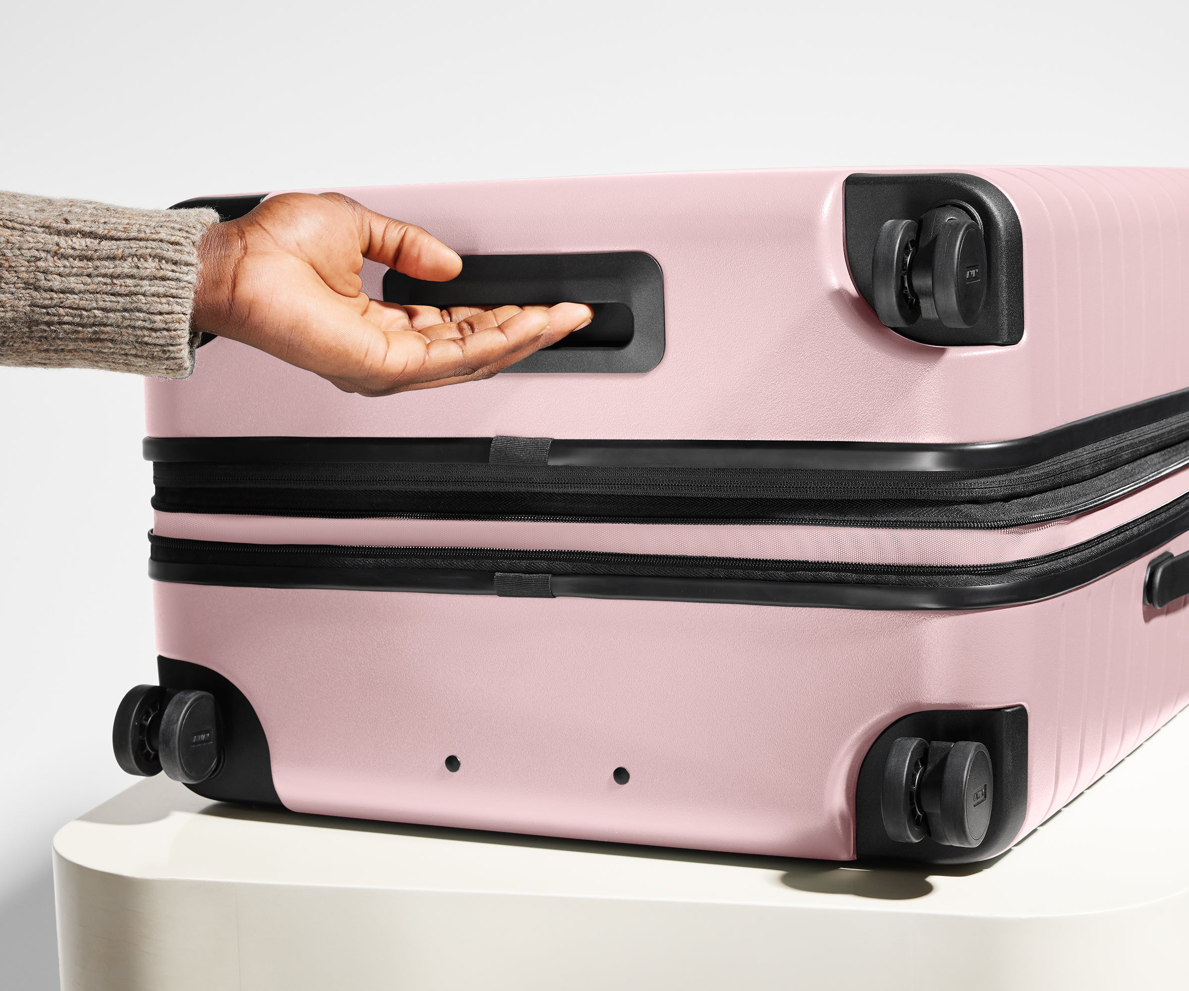 The Large Flex suitcase in Blush Pink shown from below highlighting the underside grab handle