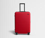 Red suitcase with a black handle on a light gray background