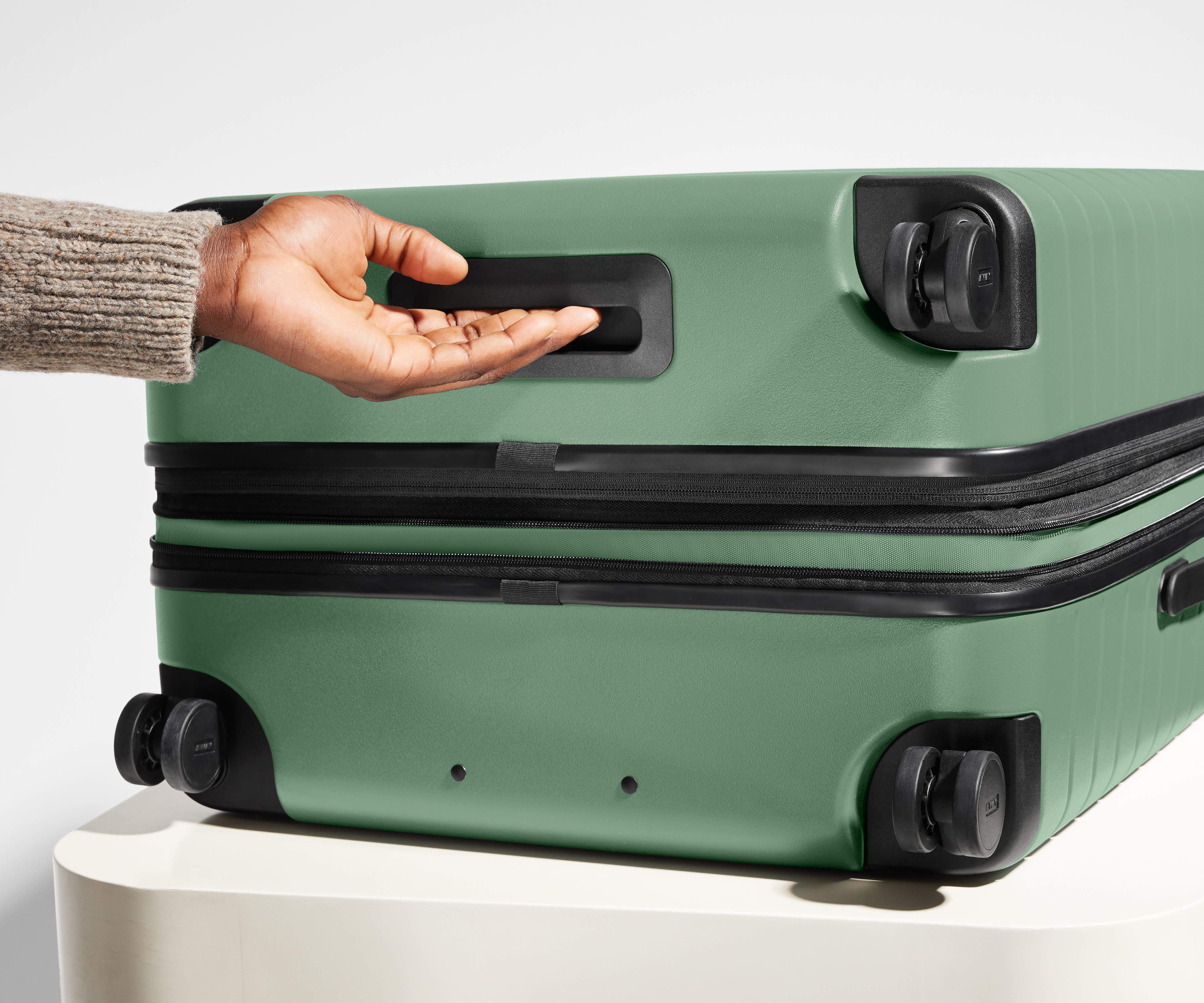 The Medium Flex suitcase in Sea Green shown from below highlighting the underside grab handle