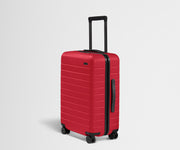 Red suitcase with black handle and wheels on a light gray background