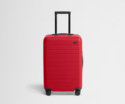 Red suitcase with black wheels on a light gray background