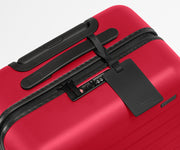 Red suitcase with black handle and tag on a white background