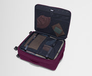 The Softside Large suitcase in Plum Purple shown open on its side and packed with Away's packing organizers to show capacity and the interior compression system, designed to help you pack more in